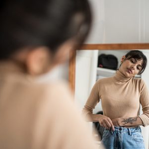 Young woman getting dressed in front of a mirror at home